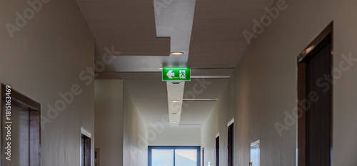 Wallpaper Mural A green fire escape sign hangs from the ceiling, showing an exit sign green light box with a running man and an arrow pointing right for safety and evacuation. Torontodigital.ca