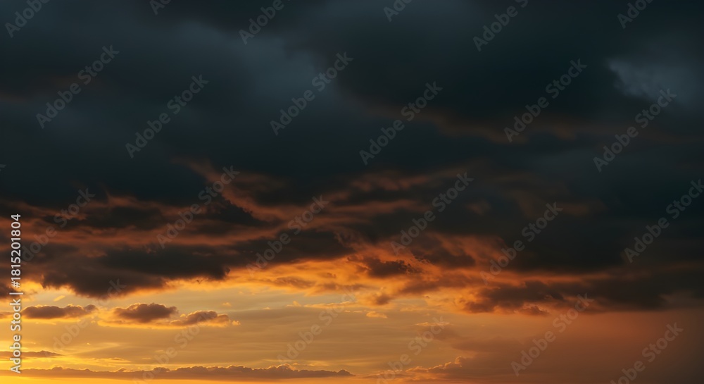 Fototapeta premium Dramatic dark clouds meet golden sunset light for stunning atmospheric background
