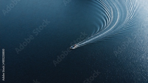 Aerial View of a Single Motorboat Creating Ripples on a Serene Blue Lake Surrounded by Calm Water Under Bright Sunlight