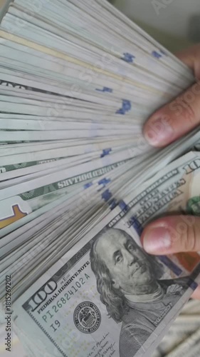 vertical screen closeup hands fanning hundred-dollar bills, large stacks on table, neat bundles and mixed denominations, bright studio light, careful counting by small business owner, upbeat