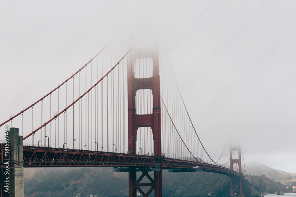 Obraz premium Golden Gate Bridge emerging through layers of soft morning fog.