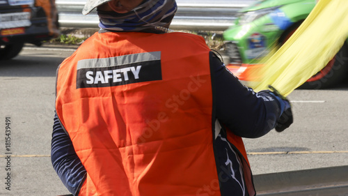 Φωτογραφία Professional race marshal from behind wearing an orange safety vest and white helmet