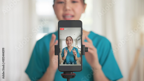 Young adult woman Gen Z asia people anti aging expert modern nurse live talk viral video selfie camera on mobile phone app mental health care. Online sharing digital virtual asian vlogger filming.