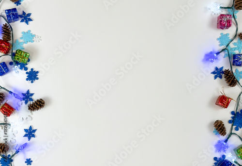 Winter holiday border with lights pinecones and colorful decorations on white background