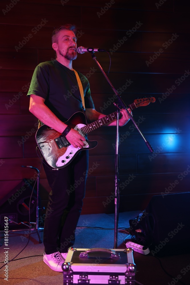 Fototapeta premium Handsome man playing electric guitar on stage