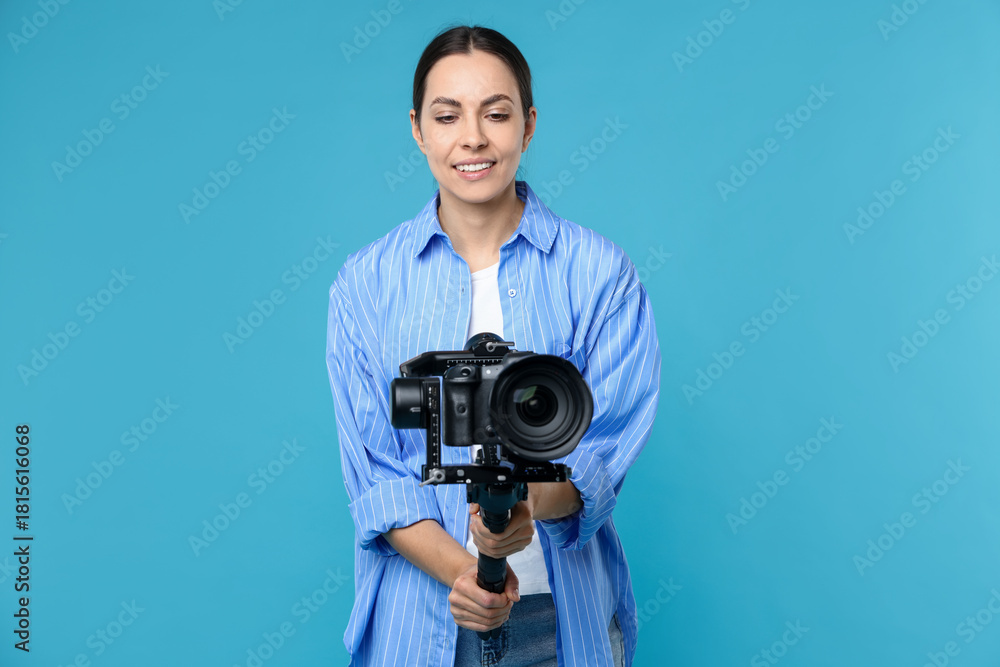 Obraz premium Videographer using gimbal stabilizer with camera on light blue background