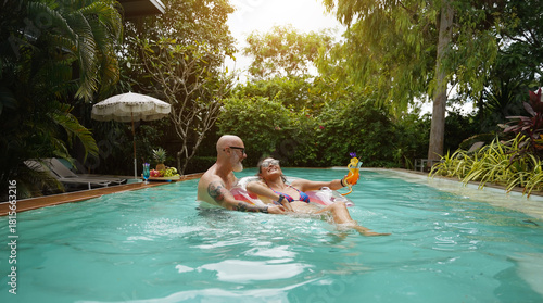 A man and a woman are having fun and drinking cocktails in the pool.