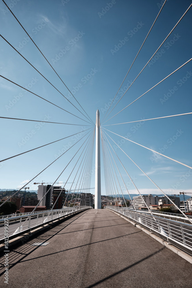 Naklejka premium Modern cable-stayed bridge with clean geometric lines against a clear blue sky, ideal for architecture and infrastructure concepts