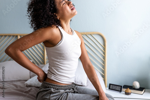 Woman feeling back pain waking up in bed
