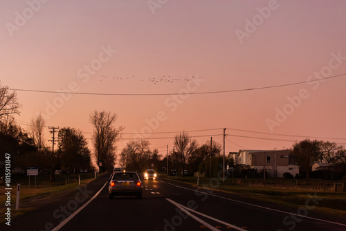dusk sky above road with car traveling onward and powerlines overhead