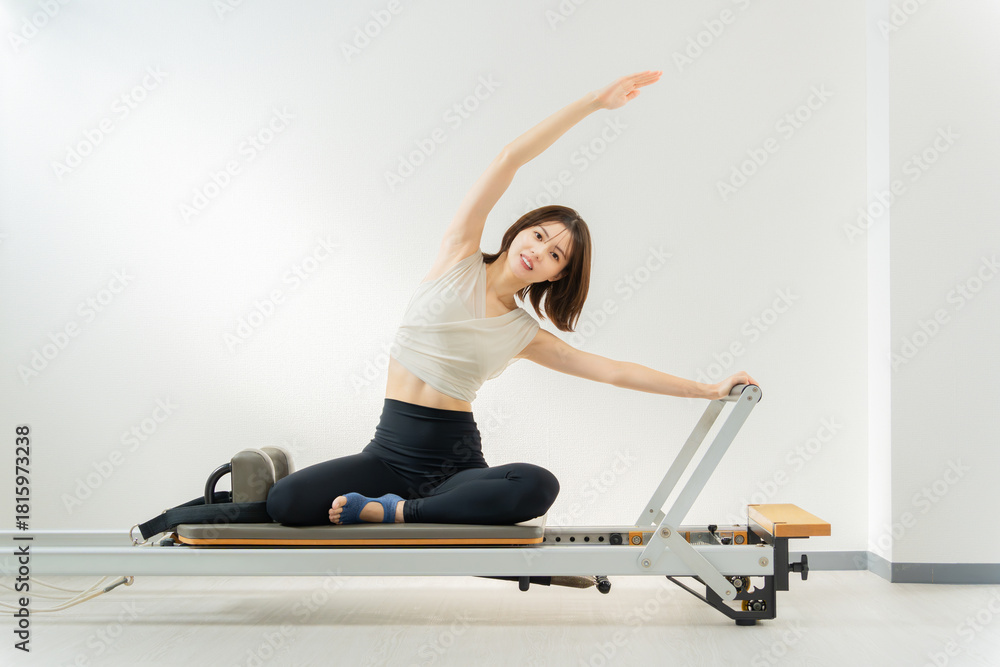 Naklejka premium ピラティス女子 日本人女性がリフォーマーでポーズ