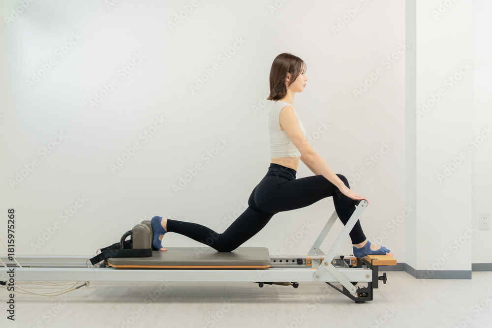 Naklejka premium ピラティス女子 日本人女性がリフォーマーでポーズ