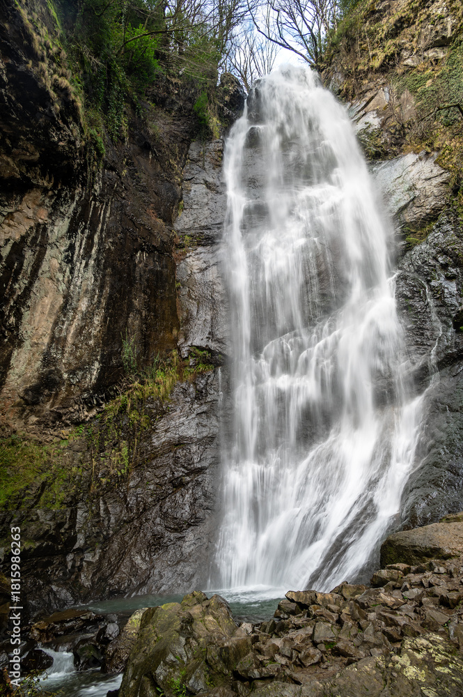 Obraz premium Tall Mirveti Waterfall near Gvara, Georgia, cascading over rocky cliffs surrounded by lush forest. A scenic natural attraction in the Caucasus Mountains.