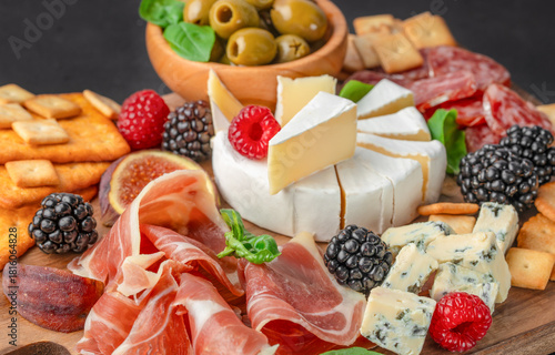 Rustic charcuterie board with assorted cheeses, cured meats and fresh berries close up
