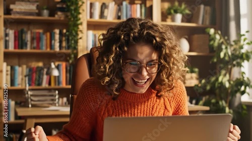 Excited woman celebrating success with arms raised in front of laptop