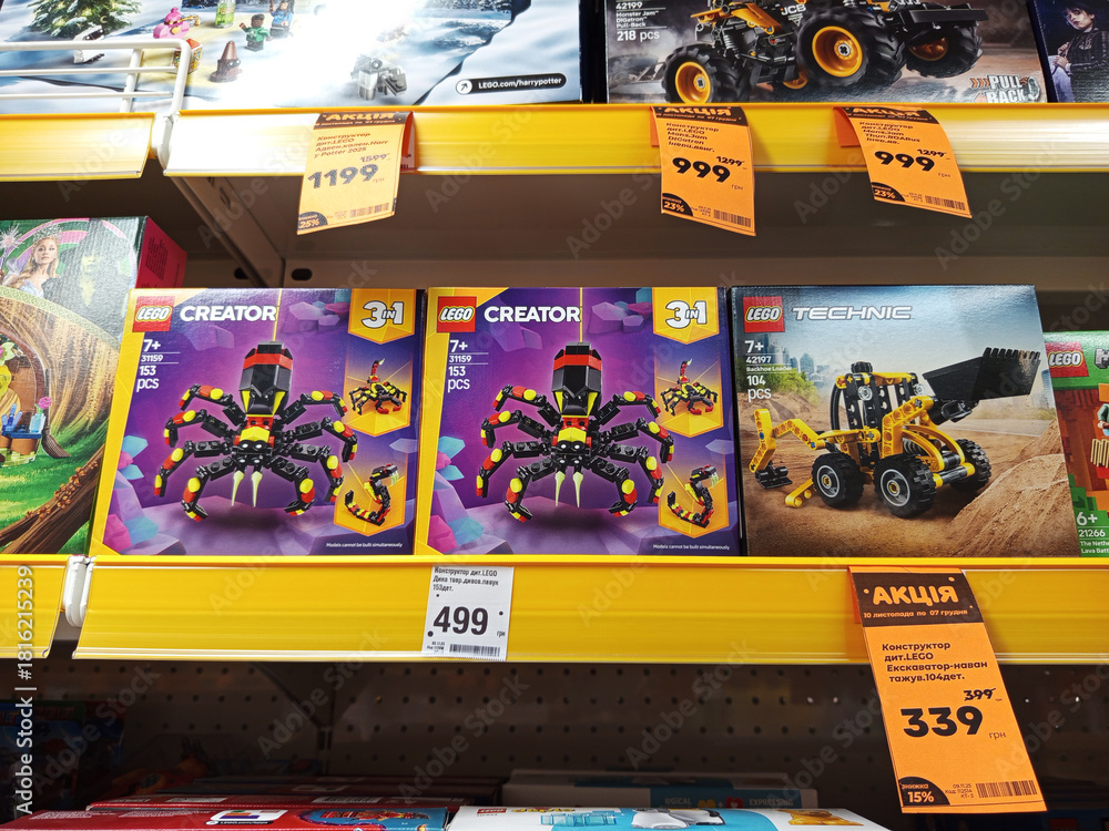 Naklejka premium Zvyagel, Ukraine - November 20, 2025: LEGO Creator 3-in-1 spider and Technic construction vehicle sets displayed on store shelf, showcasing colorful packaging and engaging design for children
