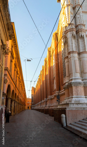 Sunlit Medieval Street and Basilica Facade in Bologna, Italy