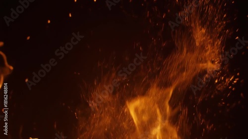 Experience the dynamic energy of a roaring blaze, where glowing embers dance against the darkness. A powerful, intense visual of raw, untamed heat, illuminated by vibrant, scattered sparks