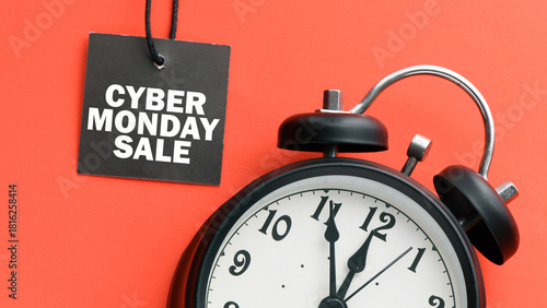 CYBER MONDAY SALE words on a small tag and red background with a clock. View from above.