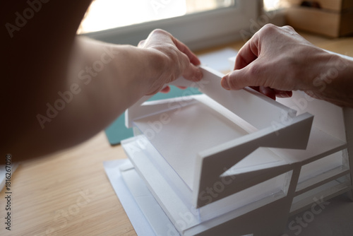 Close-up of an architect's hands building a white scale model. A concept for creativity, design, engineering, and construction projects.