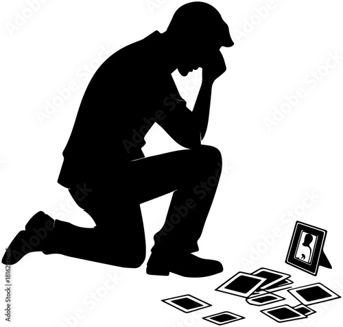 Silhouette of Person Kneeling in Remembrance with Scattered Photos