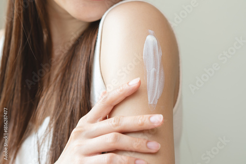 Health skin care, beauty smile asian young woman, girl  hand applying, putting moisturizer on her arm, shoulder after shower bath at home. Skin body cream moisturizing lotion, routine in the morning.