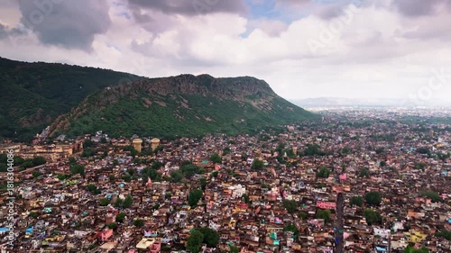 Cinematic drone view of Alwar city with green landscapes and Aravalli mountain backdrop.