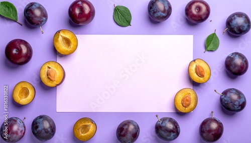 Fresh plums arranged around a blank sheet on a purple background ready for a recipe or artistic display