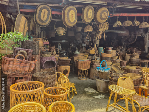 ​Traditional rattan and bamboo handicraft shop. Collection of handmade woven wicker baskets, furniture, and natural home decor display.