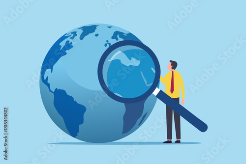 Global business analysis man with magnifying glass inspecting the world