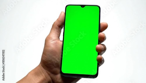 Hand holding a smartphone with a green screen