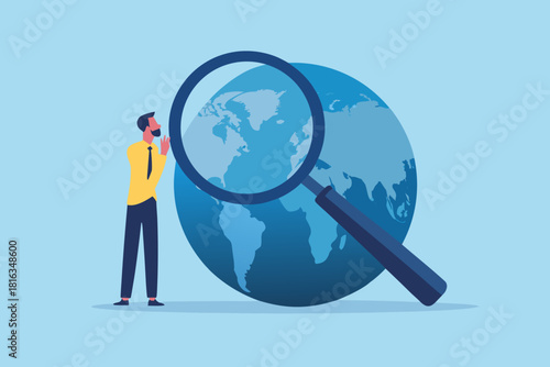 Man with magnifying glass examining globe for global business opportunities