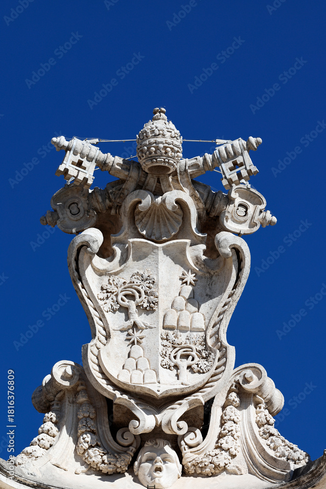 Obraz premium St. Peter’s Basilica. Papal coat of arms with crossed keys and tiara carved in stone above Vatican entrance.