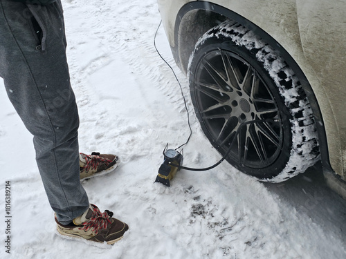 Pumping Car Tire in Snowy Winter Conditions