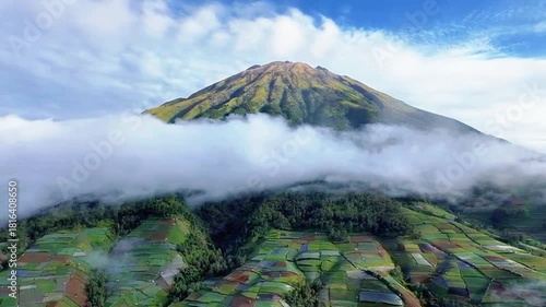 a video of a volcano with wispy clouds and clear skies