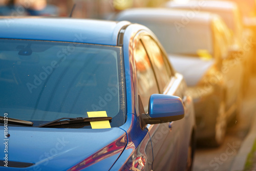 Violation parking ticket on car windshield. Yellow payment notice for parking penalty secured under car's windshield wiper, enforcement of parking laws and the cost of parking violations.