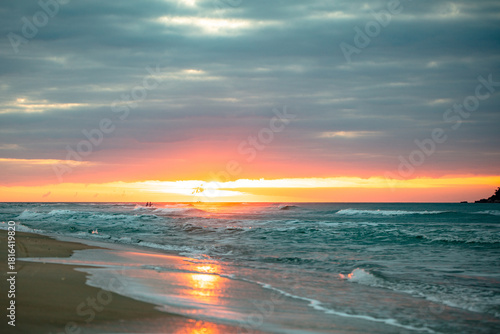 Sunrise on Campeche beach in contrast with people near the sun in Florianopolis, Santa Catarina, Brazil.