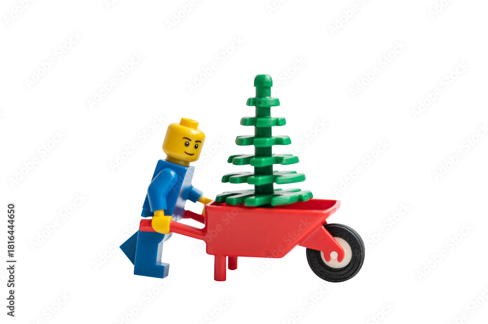 Obraz premium Lego man pushing a wheelbarrow with Christmas tree. Studio shot.