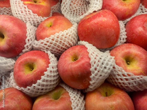 Fresh red apples wrapped in white foam net, symbolizing healthy food, organic fruit, freshness, nutrition, and natural produce for market or grocery concept.