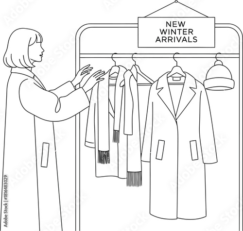 Woman browsing new winter arrivals on a clothing rack in a minimalist style