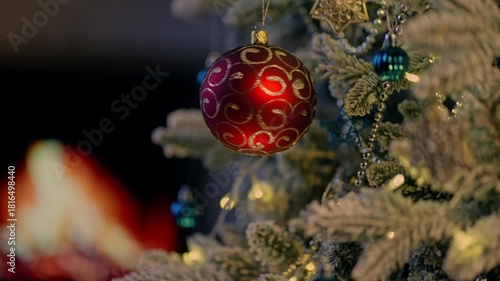 Christmas ball on Christmas tree. Cosy fireplace light in background. December winter mood. Video background for holiday ads and offer.