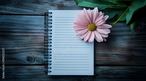 Pink flower and blank notebook on rustic wooden table top view