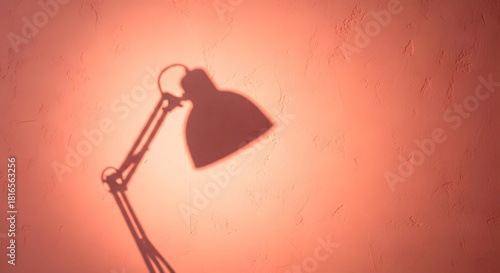 Shadow of a desk lamp cast on a textured orange wall