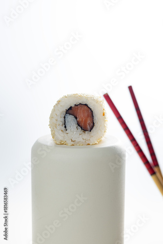 Single sushi roll with salmon and rice on light background