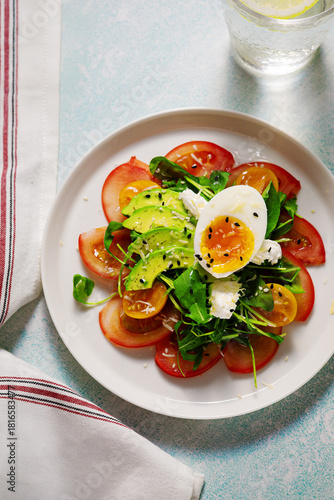 Fresh salad with tomatoes and boiled egg on white plate 