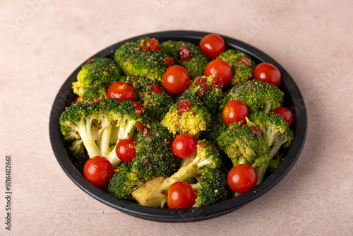 Broccoli cabbage marinated in spicy-sweet sauce and spices with cherry tomatoes. Preparing for baking. Healthy home cooking. Selective focus, close-up.