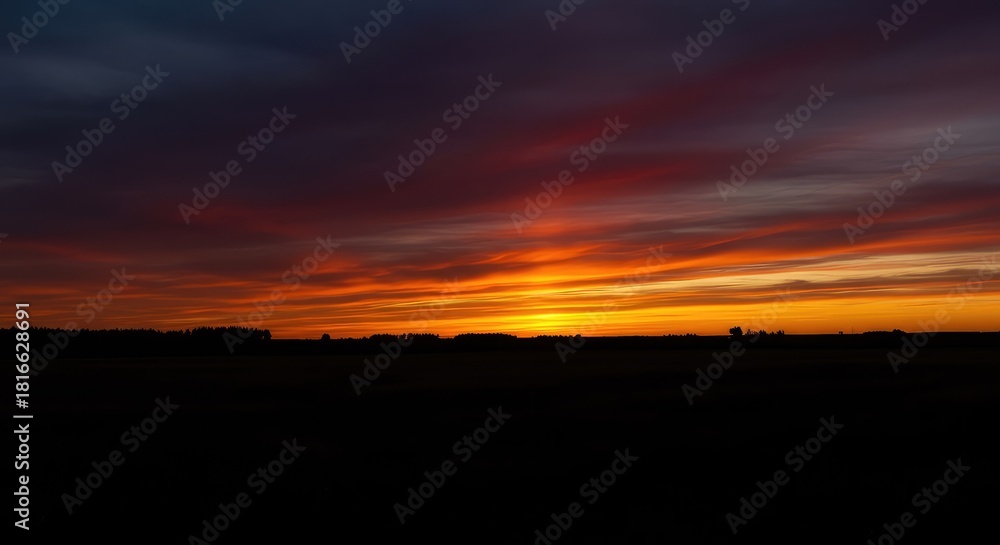 Obraz premium A dramatic, expansive landscape viewed in silhouette against the intensely colorful and fiery tones of the setting sun at twilight ,majestic ,light ,atmosphere