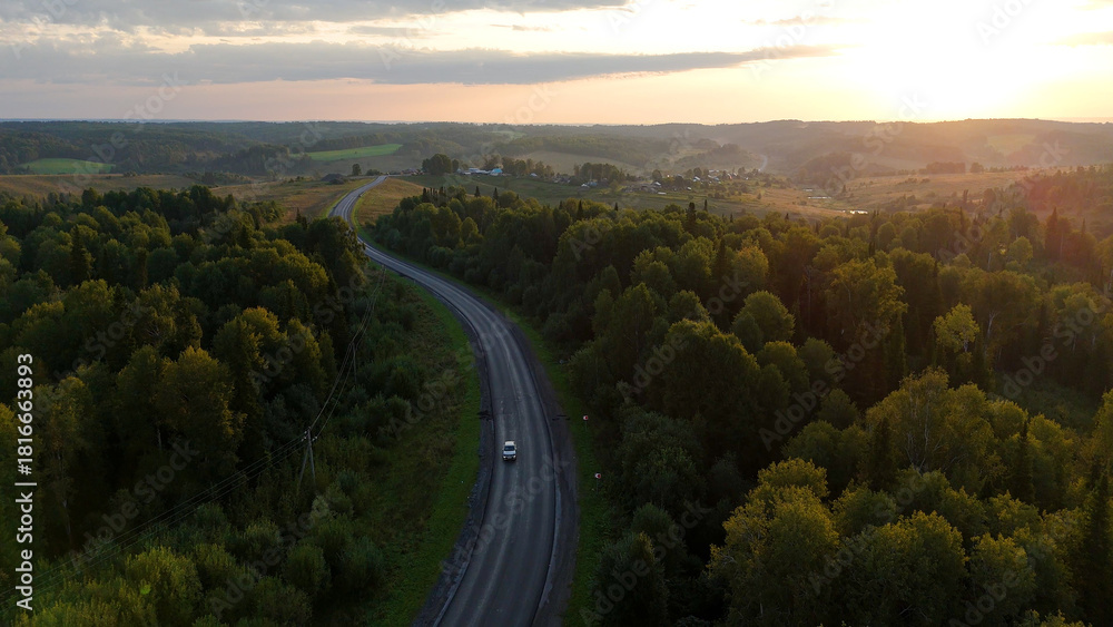 Fototapeta premium a highway in the mountains at sunset with a car driving along it