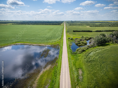 Road runs through a field with a body of water on one side