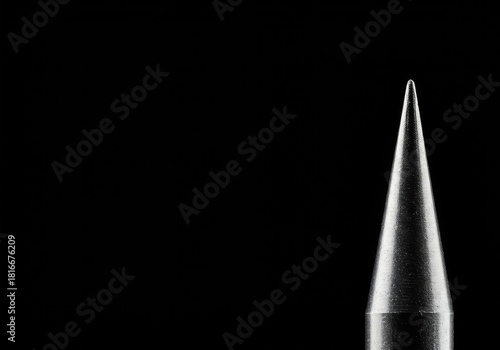 A sharp metallic spike positioned against a plain background, emphasizing danger, strength, and precision engineering. The conical tip catches the light ,close up ,cone ,end